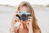 Woman With Camera Taking Summer Photos On Beach