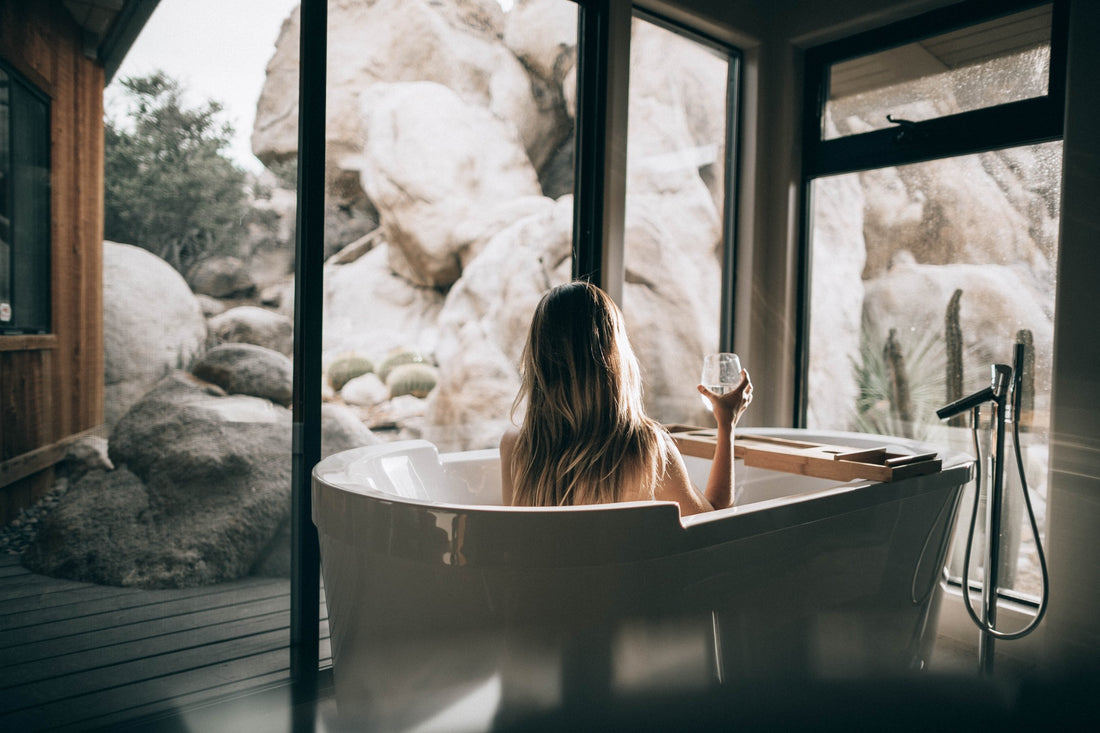 Woman Soaking In Bathtub While Drinking Glass Of Water