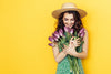 young-woman-in-green-dress-holding-bouquet-of-tulips-with-yellow-background