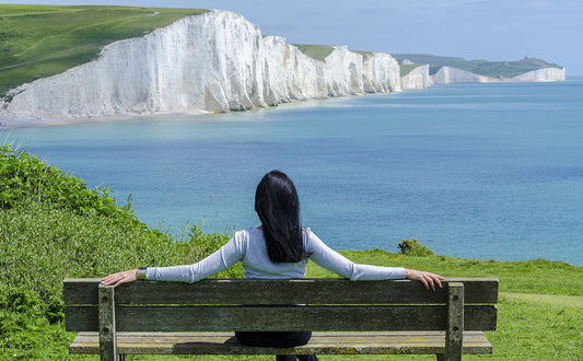 woman on bench overlooking cliffs and ocean