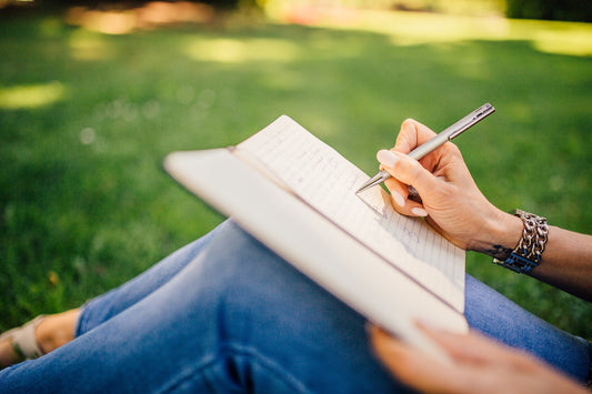 woman writing in book on the lawn