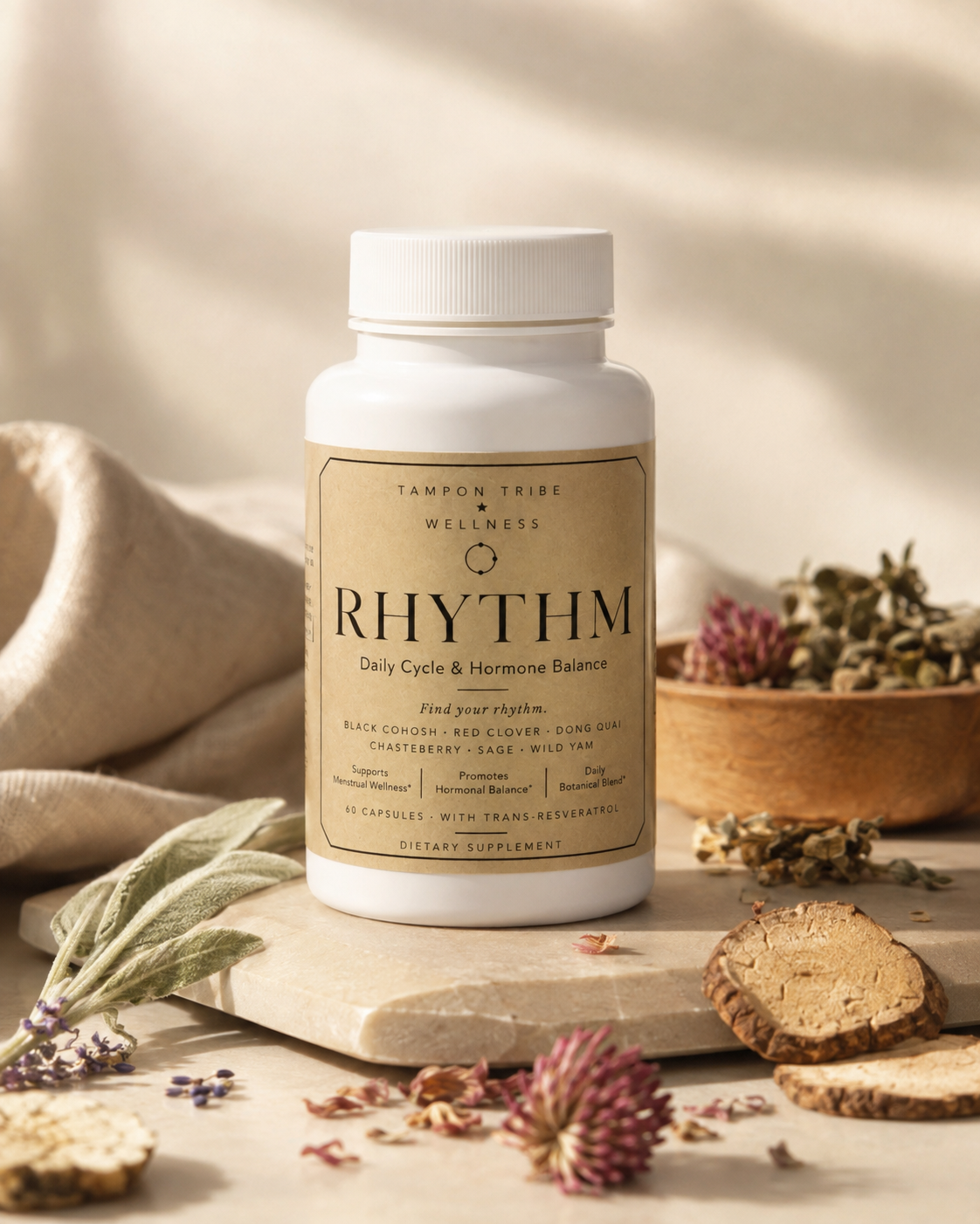 A white bottle of Tampom Tribe Wellness 'Rhythm' dietary supplement, styled on a wooden block with dried herbs, slices of root vegetables, and soft sunlight shadows.